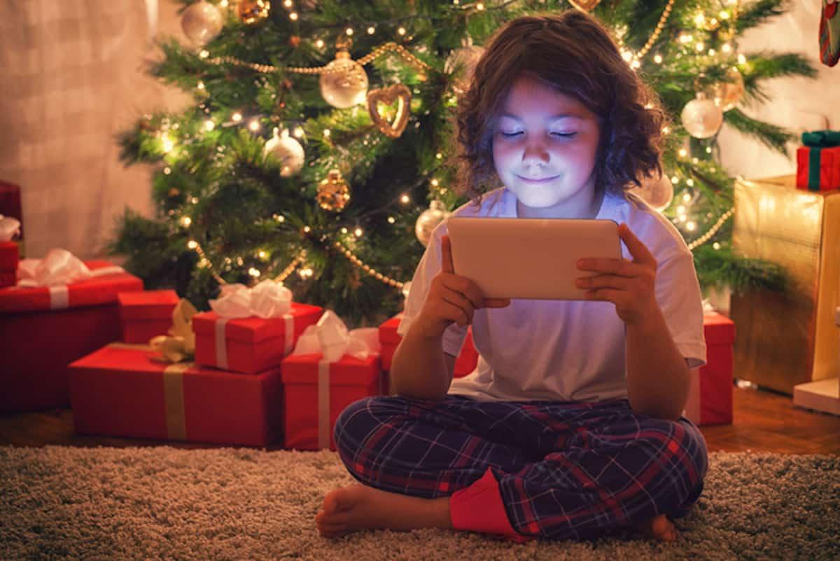 在圣诞树下使用平板电脑的女孩