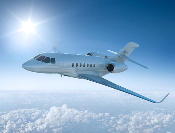 在阳光普照的天空下，一架私人商务飞机在云层之上飞行
