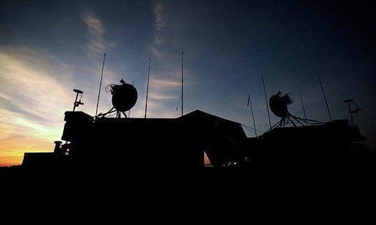 夜间的军事建筑剪影，屋顶上有卫星通信设备
