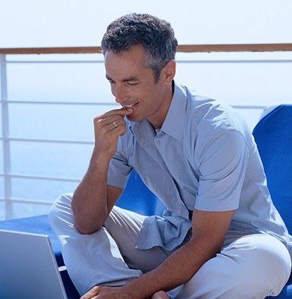 一名男子坐在一艘客船的甲板上，使用带有卫星网络的笔记本电脑