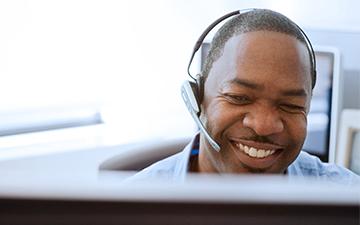  A customer support representative discussing internet packages wtih a customer on a headset, sitting behind a computer